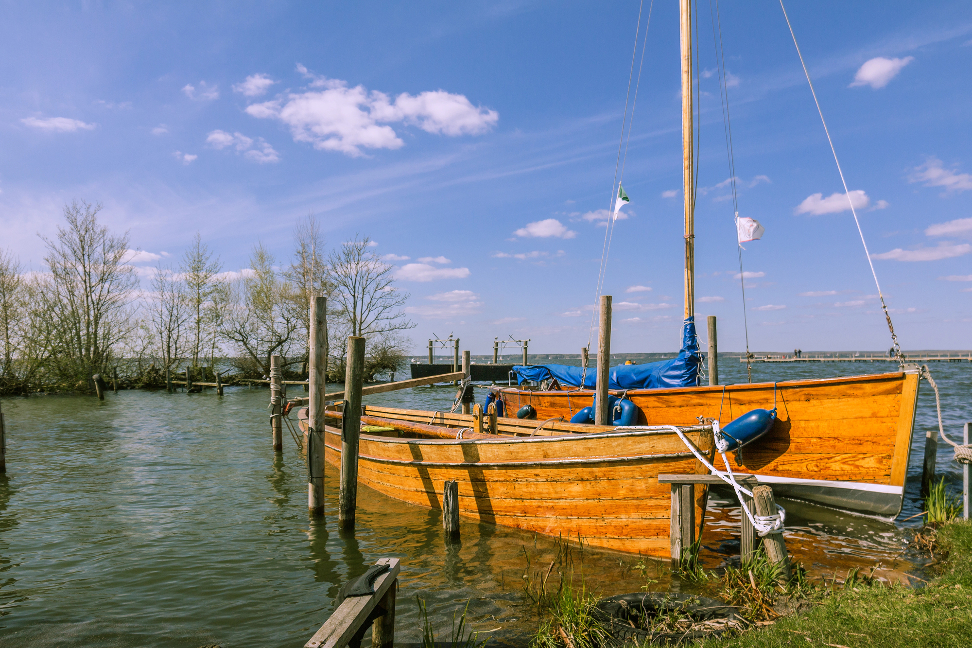Wooden sailboat tied securely to dock posts on calm water