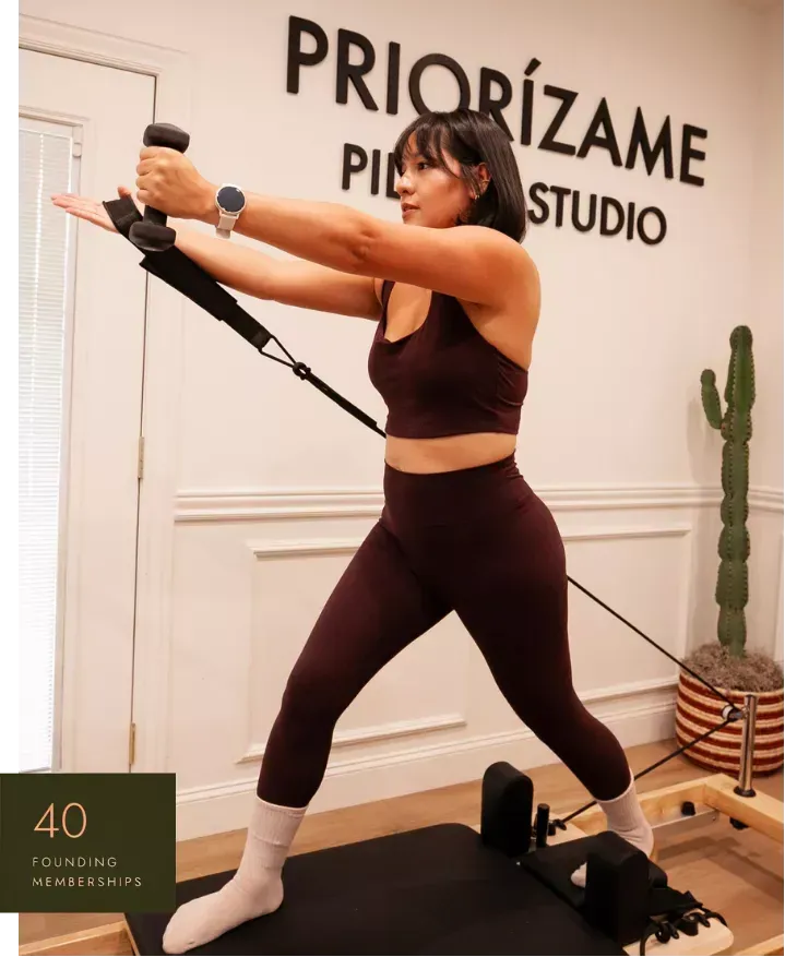 Woman in an olive green top using a Pilates reformer machine