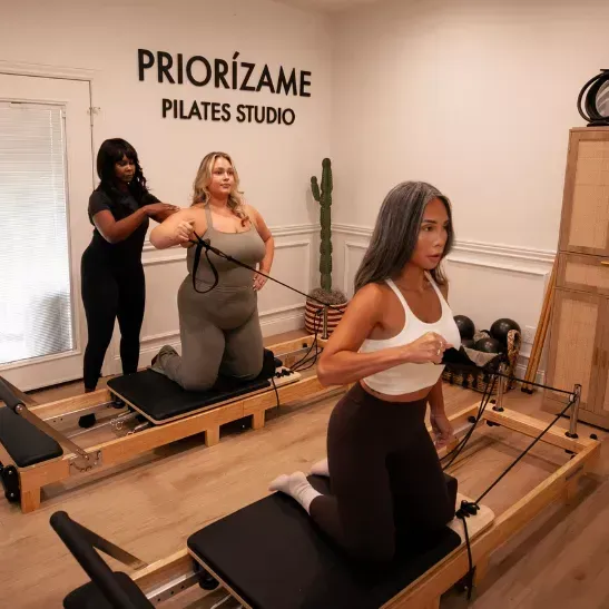 Two women smiling and laughing during a mat Pilates class.