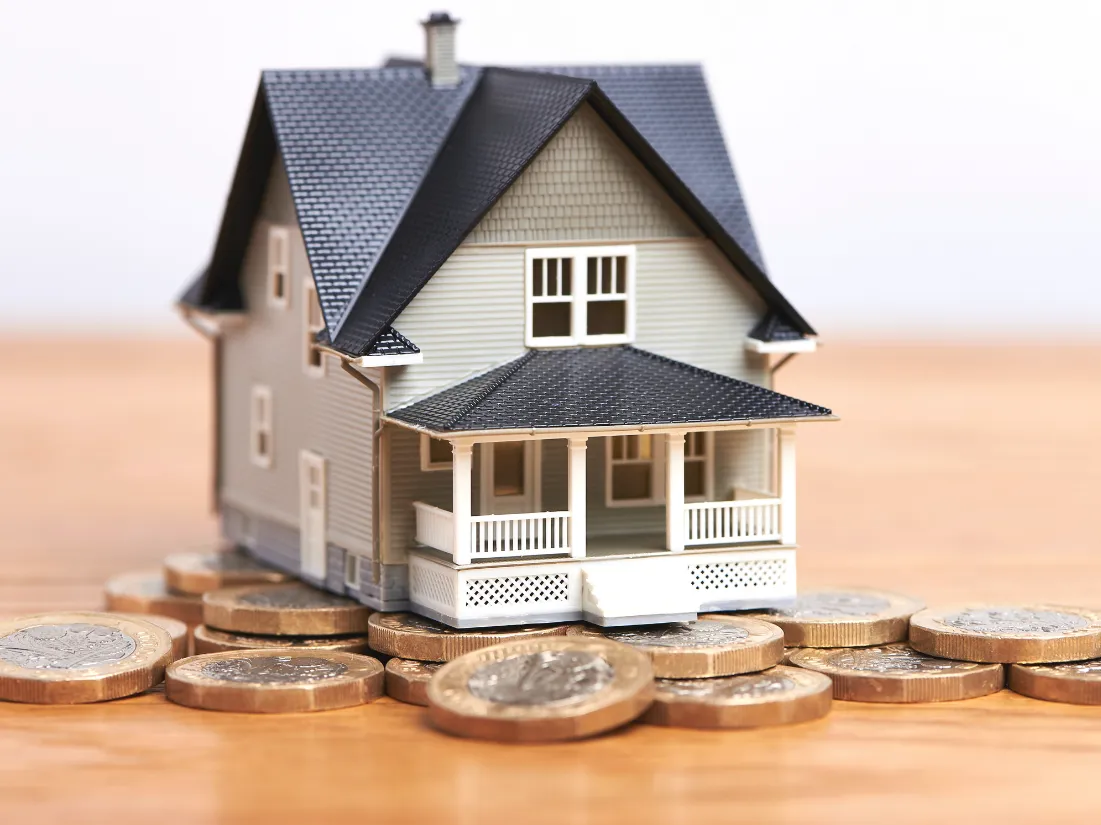 Photo of a tiny model of a home stacked on coins
