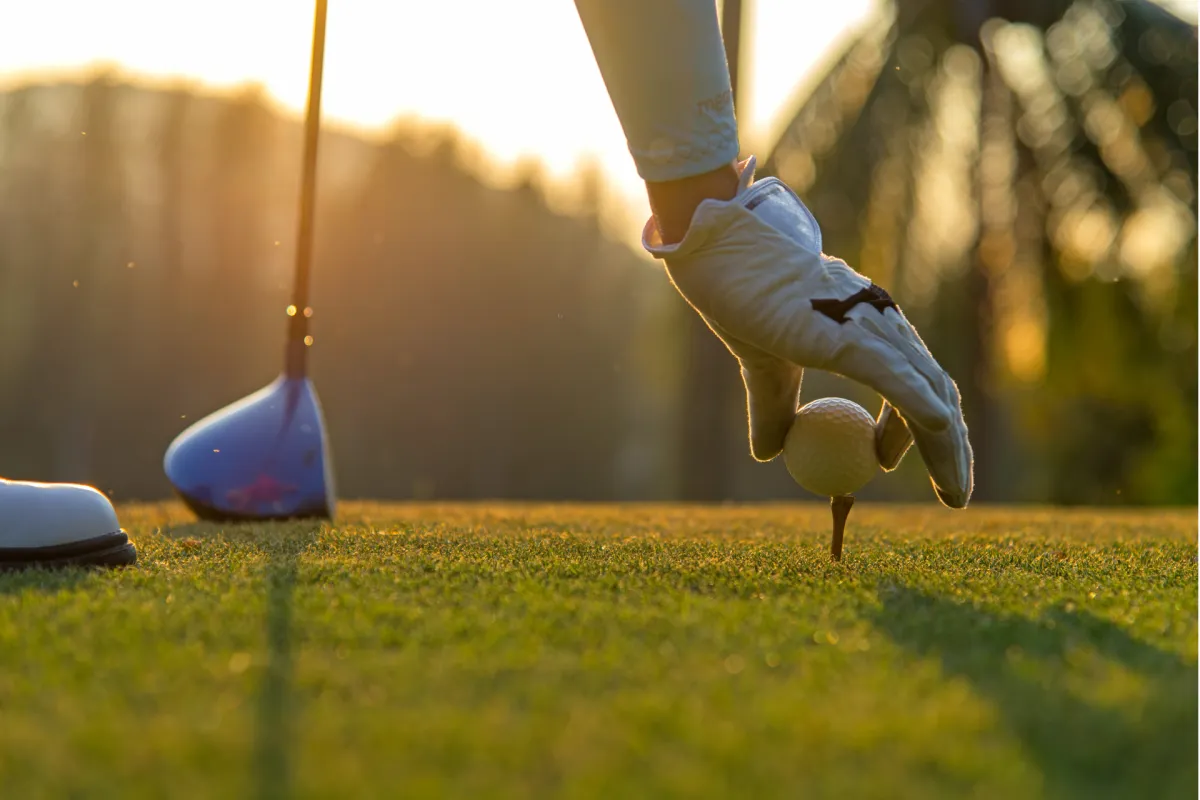 Golfer setting golf ball on a tee