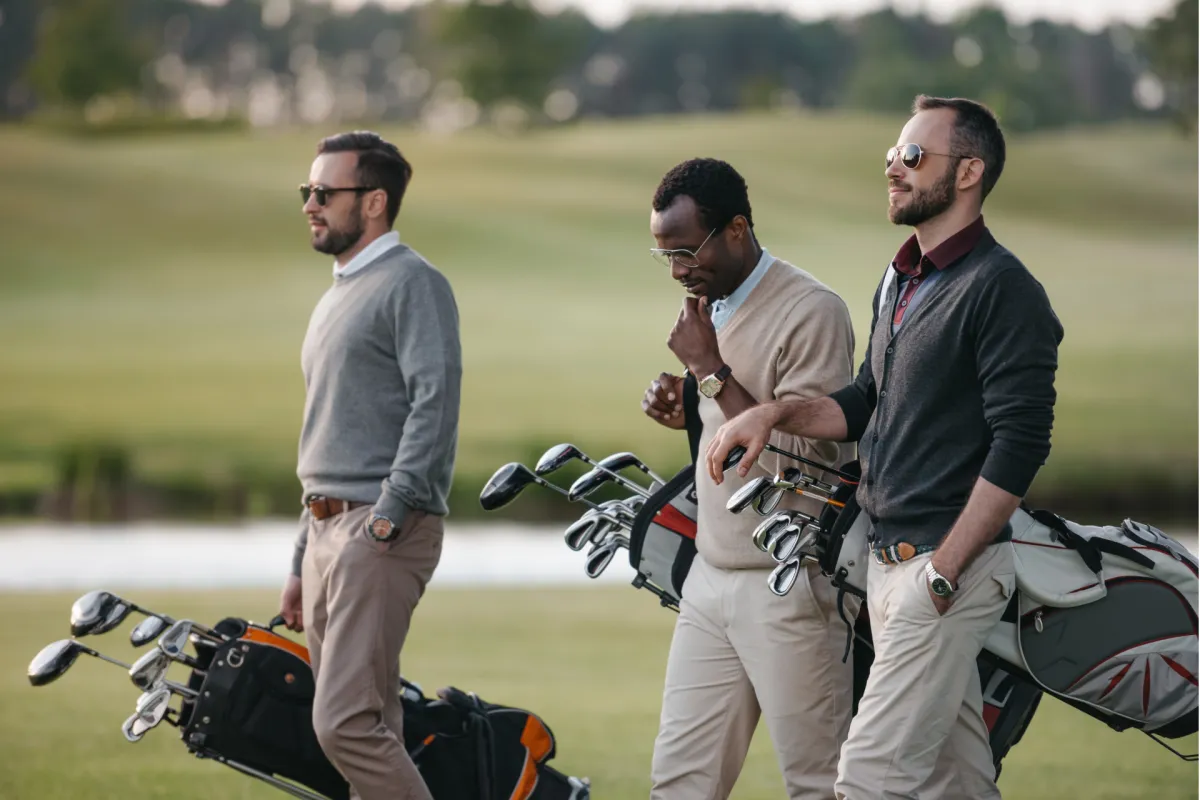 Group of three men carrying golf clubs