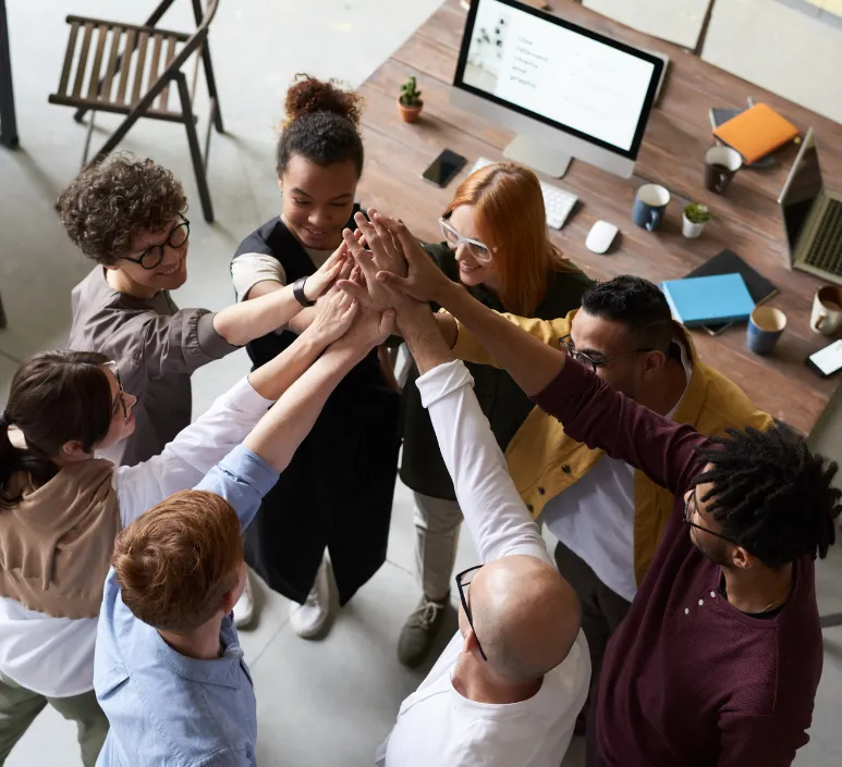 8 Diverse Colleagues Standing in Group High Five Next to Office Desk