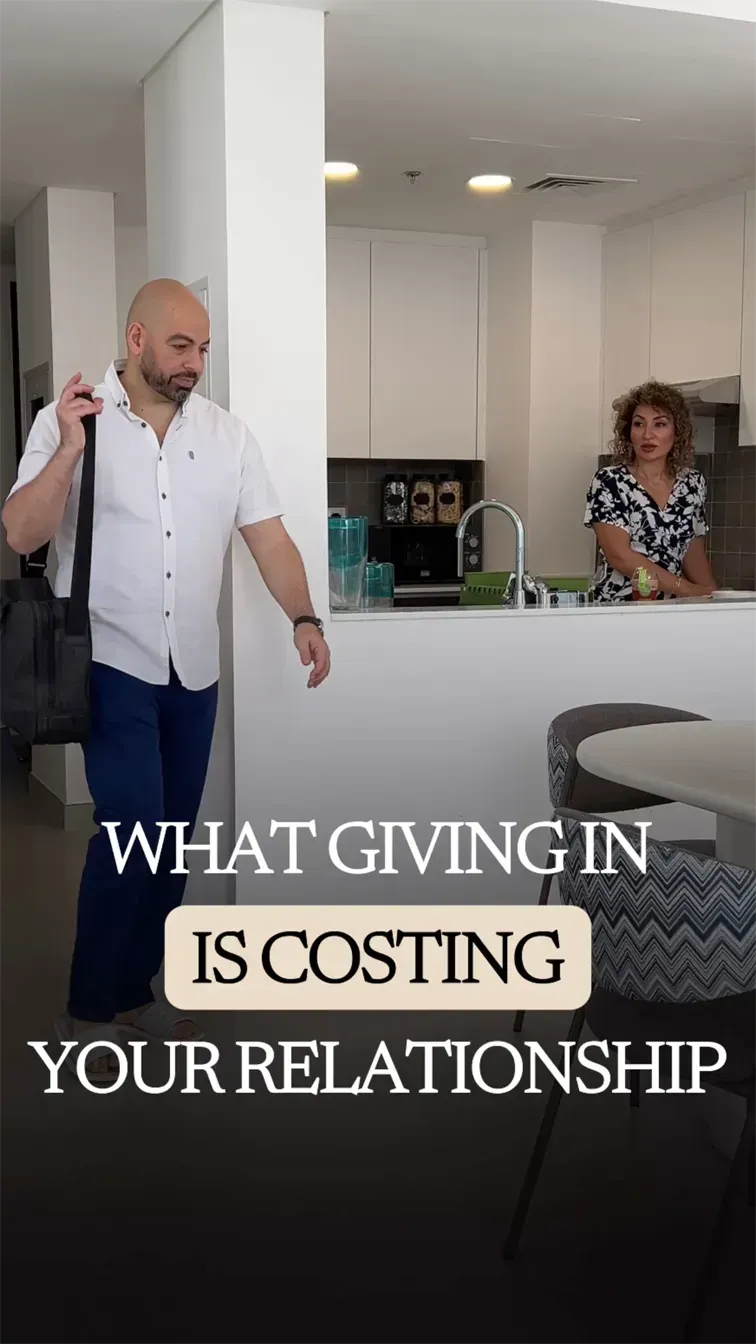 Ramy walking toward the table with a bag over his shoulder while Fatima stands alone at the kitchen counter in the background.