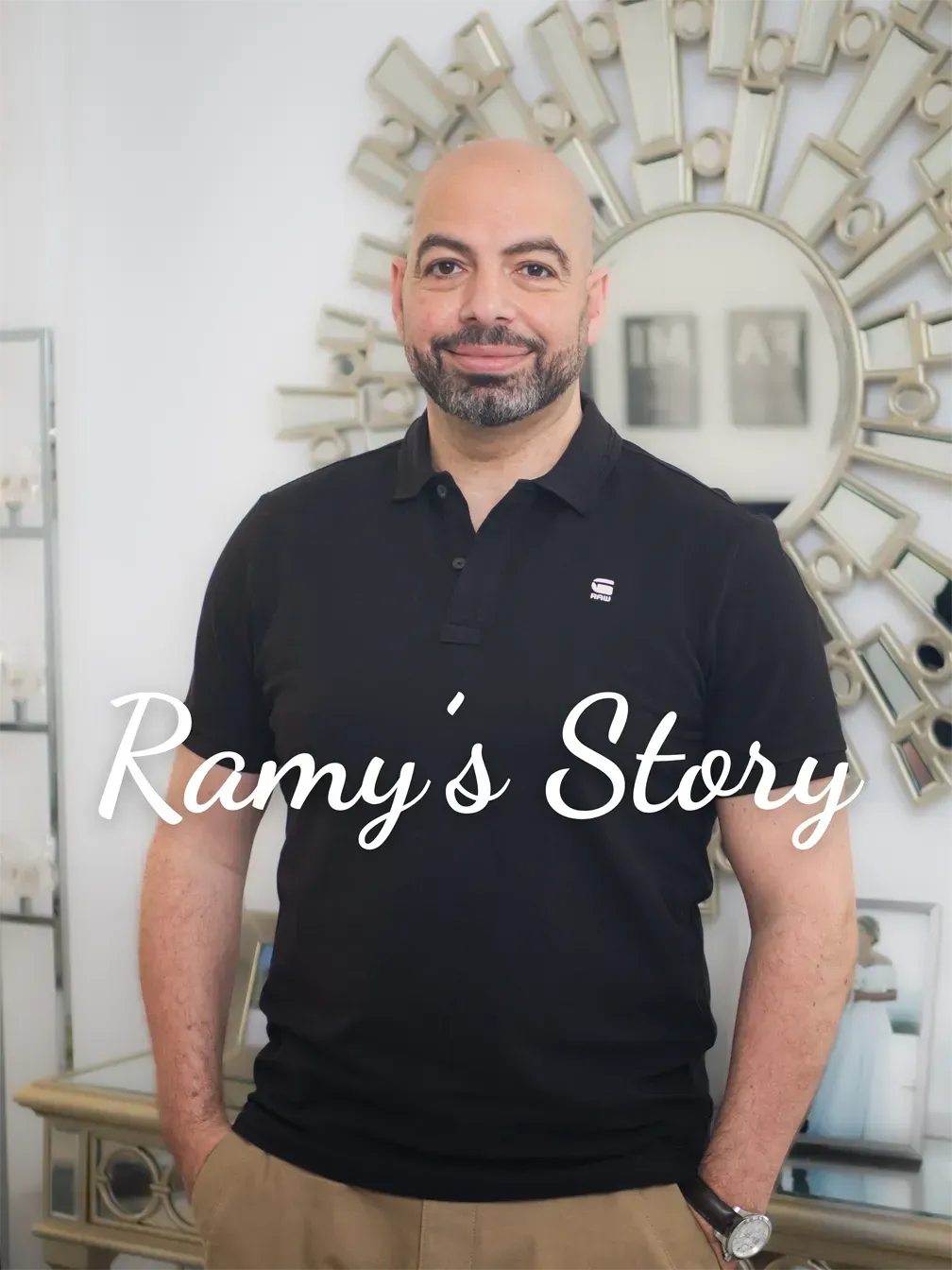 Portrait of Ramy standing in a black polo shirt, smiling directly at the camera.