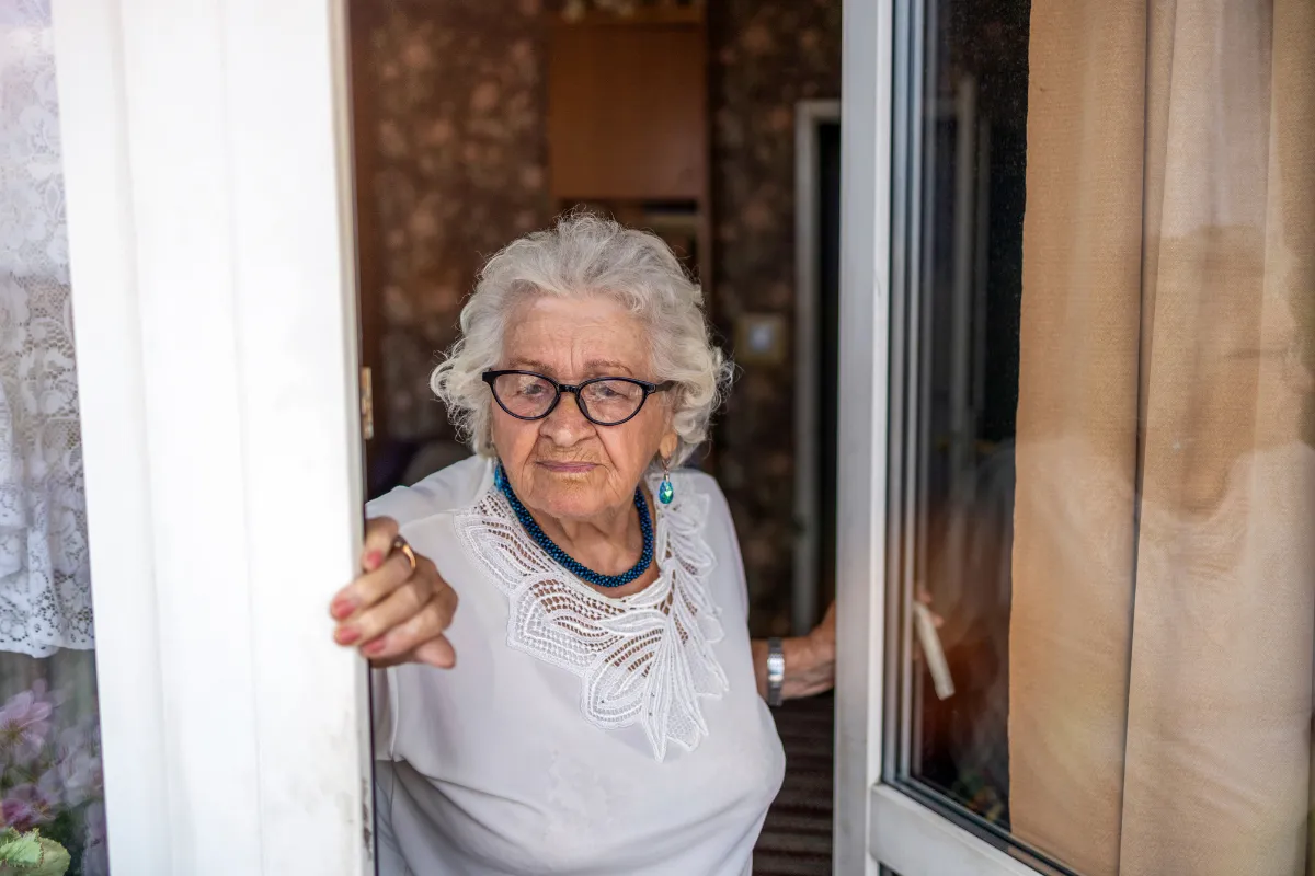 Senior homeowner standing in front of a repaired home after using a reverse mortgage to complete needed home repairs and remain in the property.