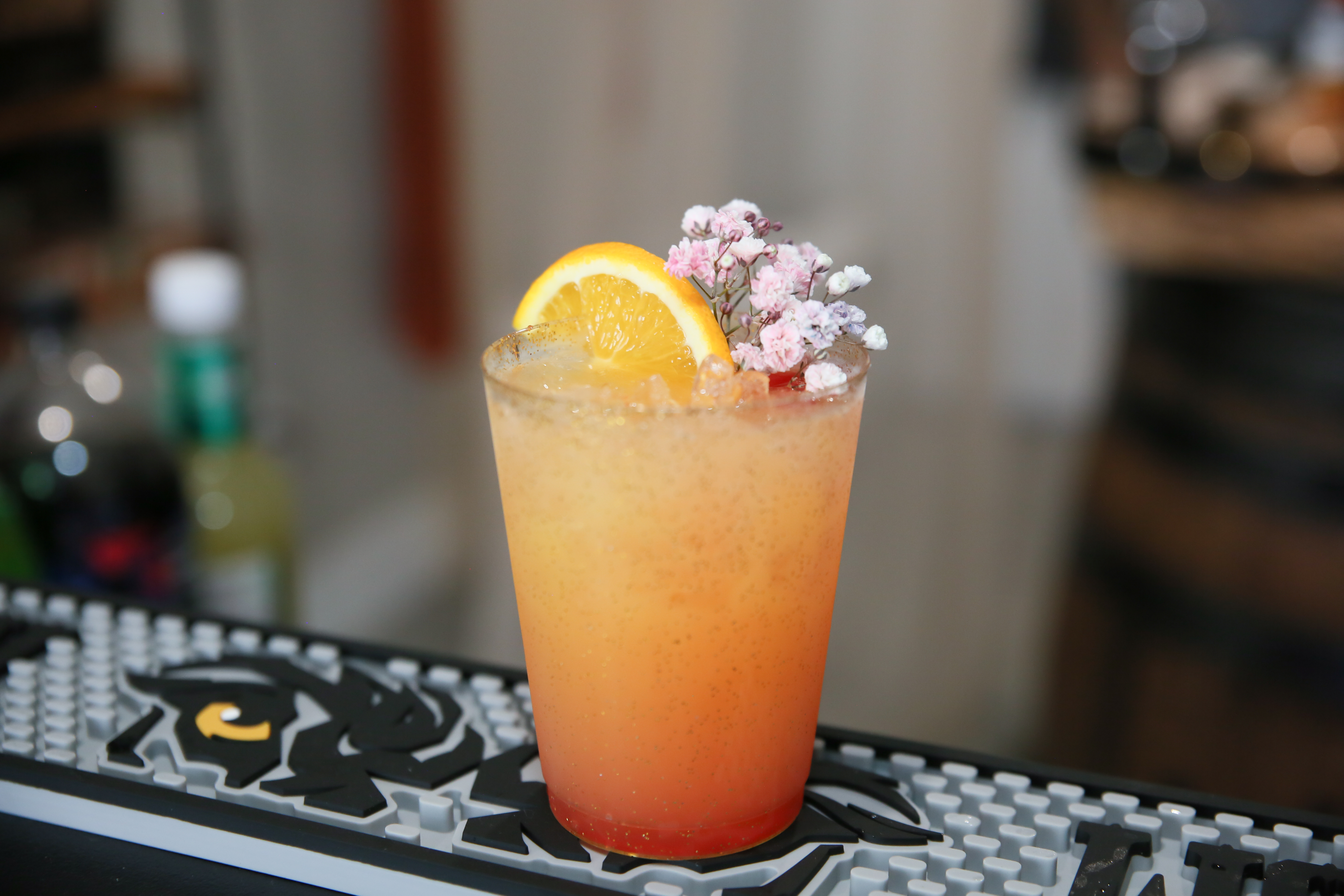 Cocktail garnished with an orange wheel and baby's breath florals in crushed ice