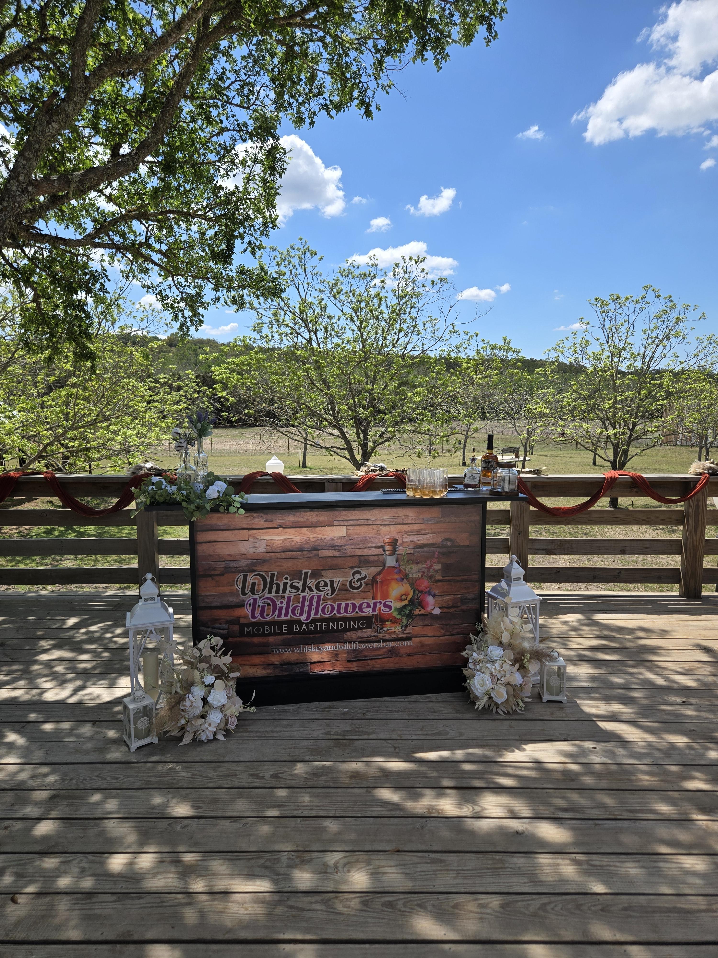 Branded Whiskey and Wildflowers mobile bar cart decorated with florals and lanterns at a Texas Hill Country venue