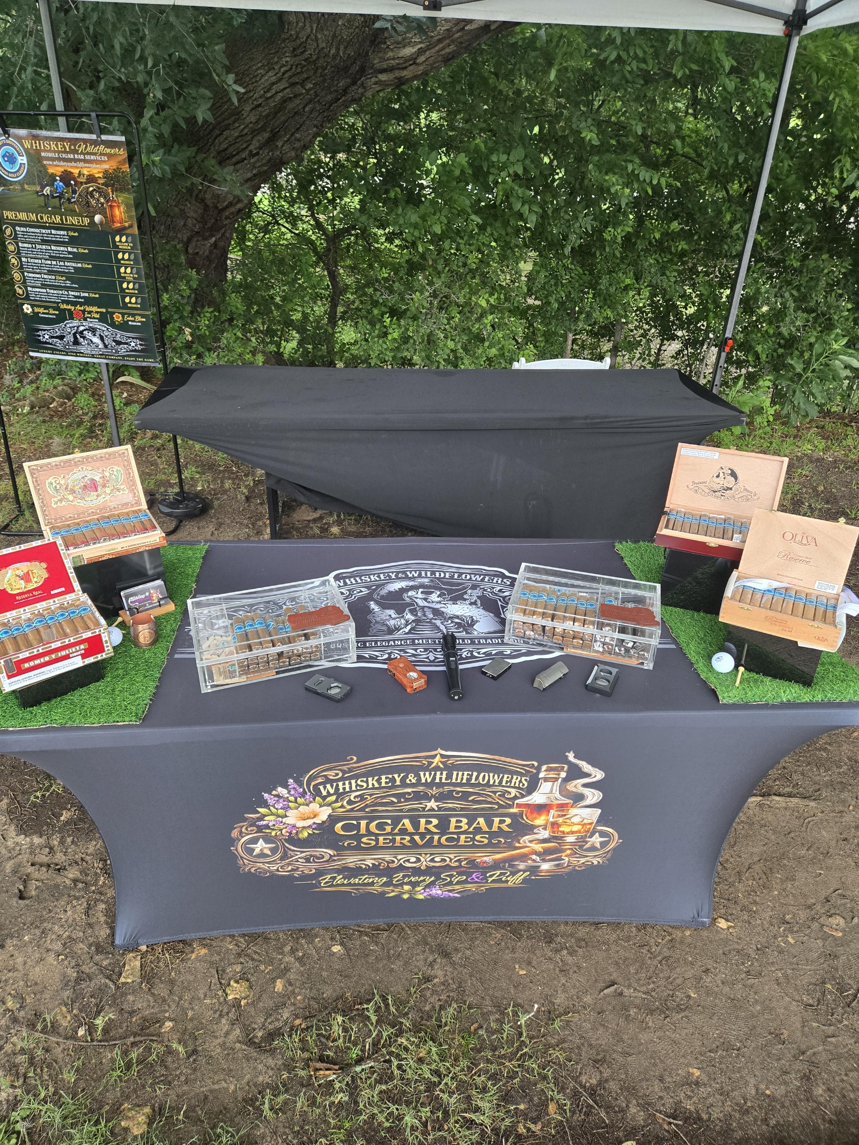 Branded Whiskey & Wildflowers cigar bar display with premium cigar lineup sign at a golf tournament