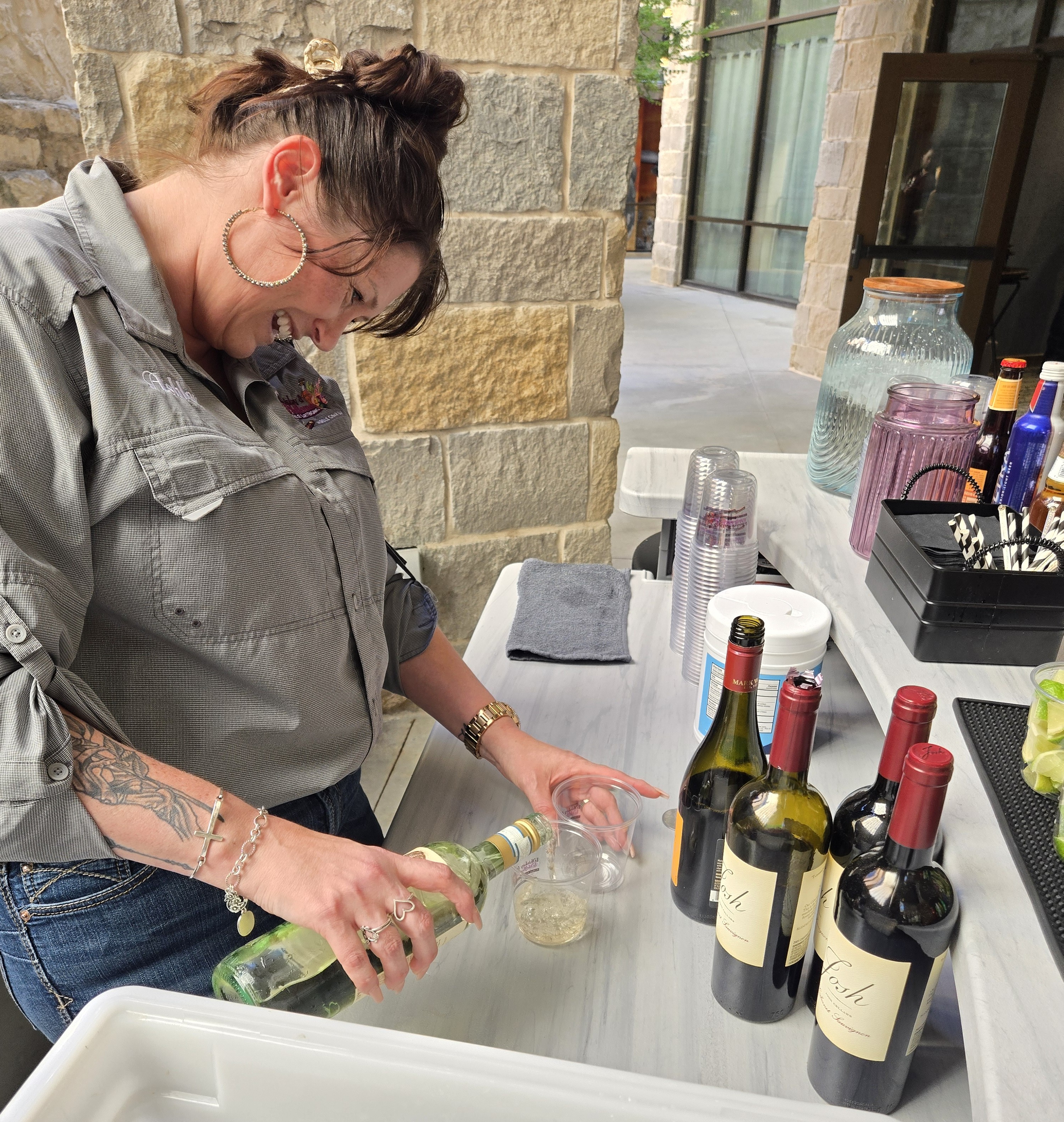 Bartender pouring wine at an outdoor stone patio bar setup for a private event