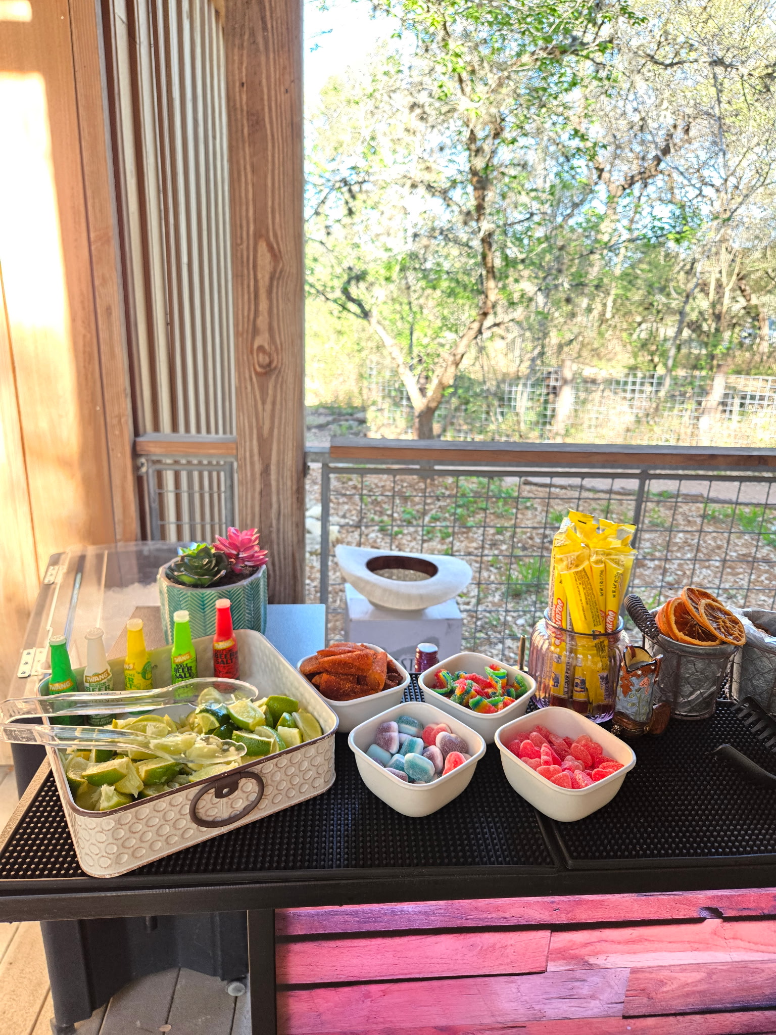 DIY cocktail garnish station with limes, candy, and flavored rimmers set up for guests