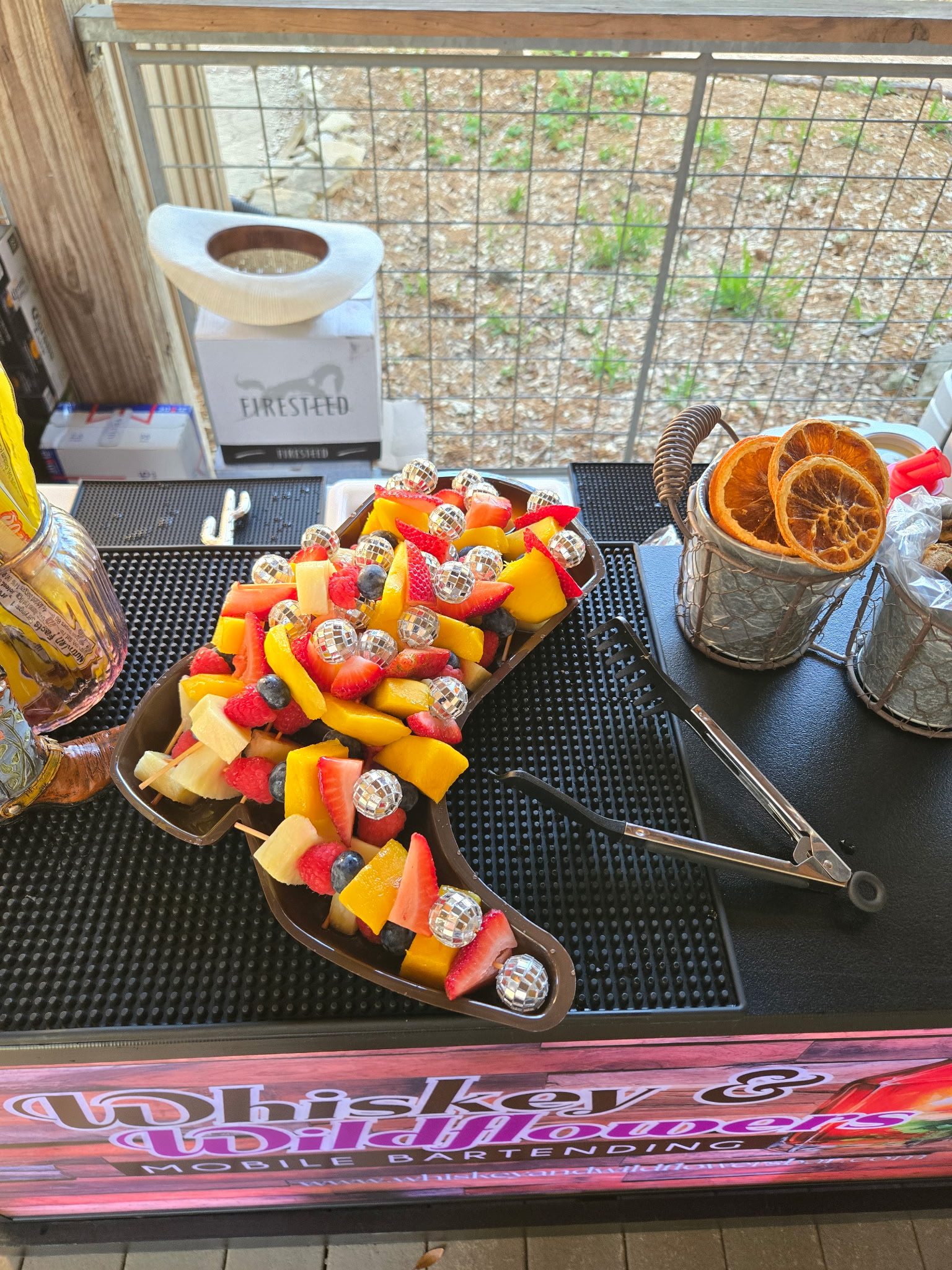 Fresh fruit skewers in a boot-shaped dish on the Whiskey and Wildflowers mobile bar