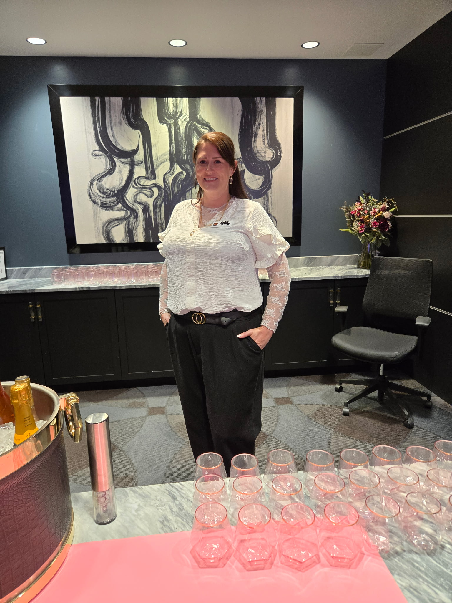 Ashley Loman, owner of Whiskey & Wildflowers, standing at a private event bar setup with champagne and glassware