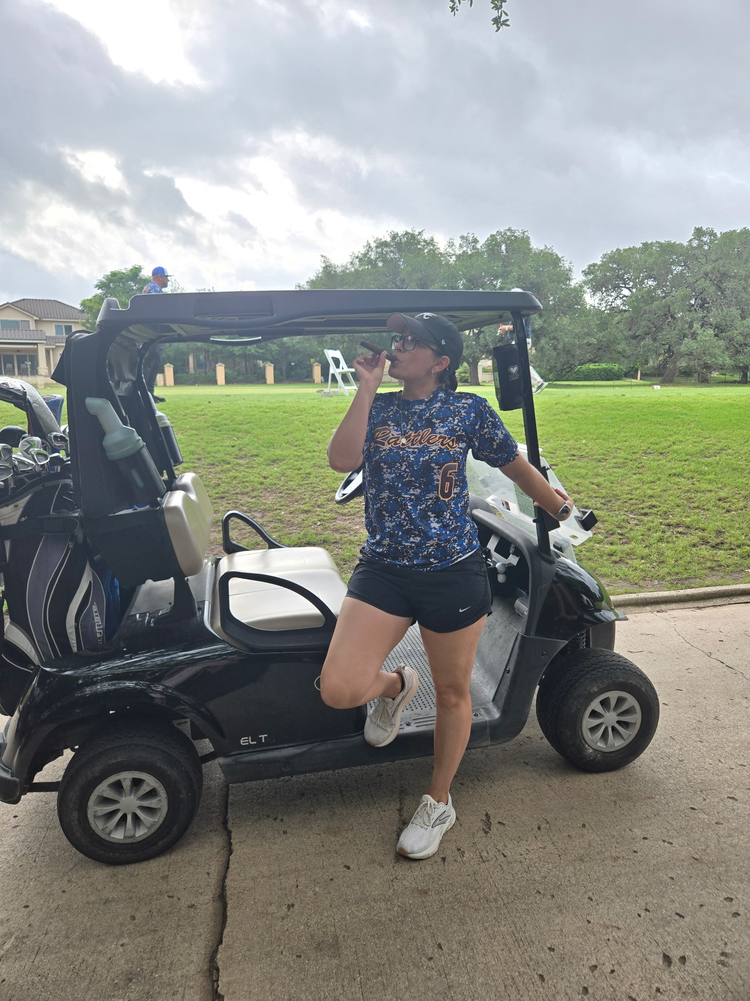 Guest enjoying a cigar by a golf cart at a Whiskey & Wildflowers golf tournament activation