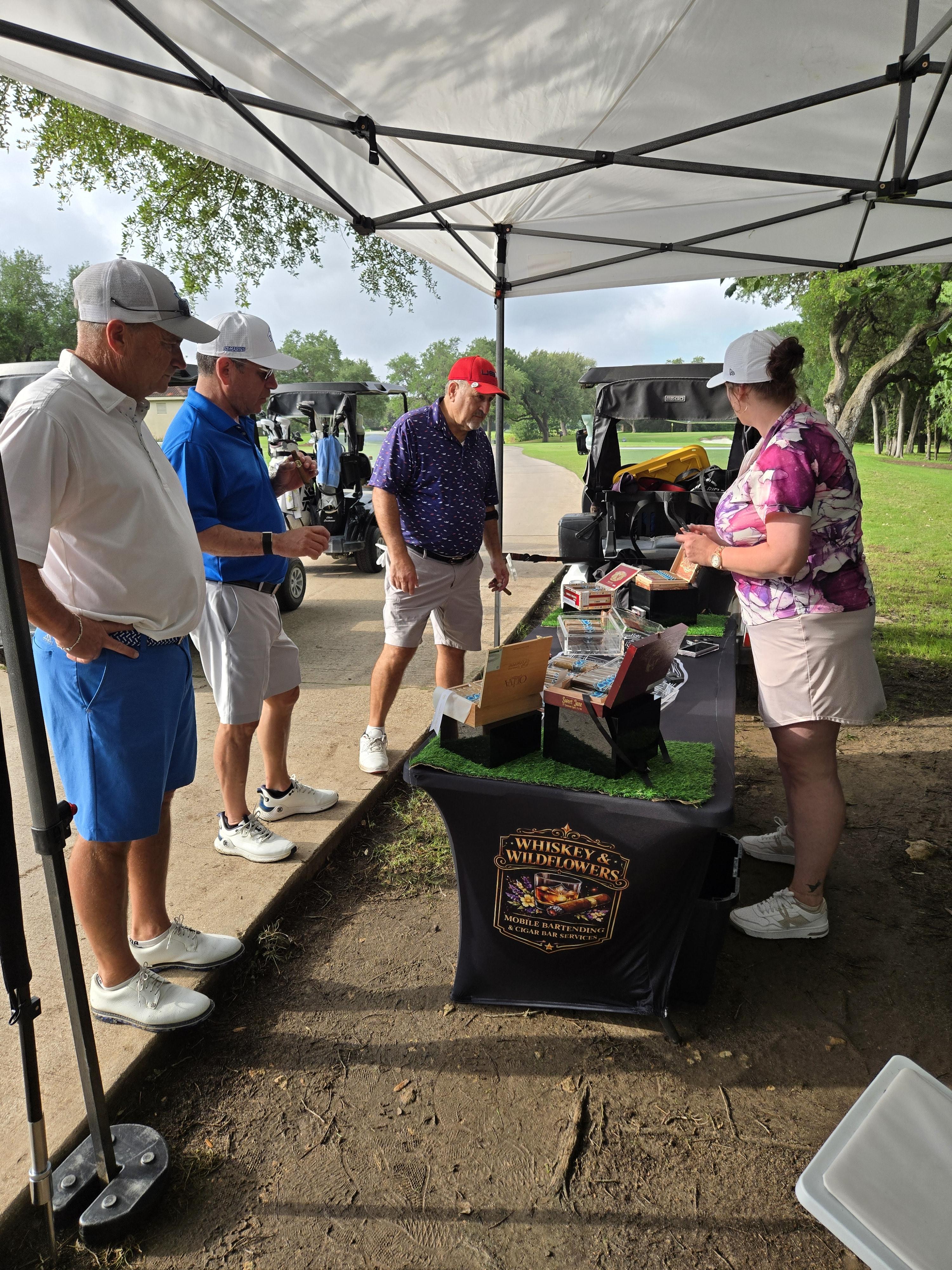 Guests interacting with a Whiskey & Wildflowers cigar bar attendant at a golf tournament activation