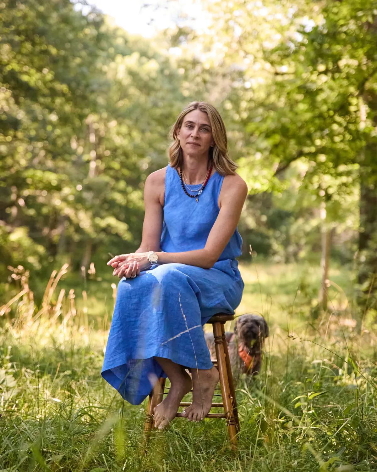 Maris Pasquale Doran seated on a stool in a field with her dog Wylie beside her