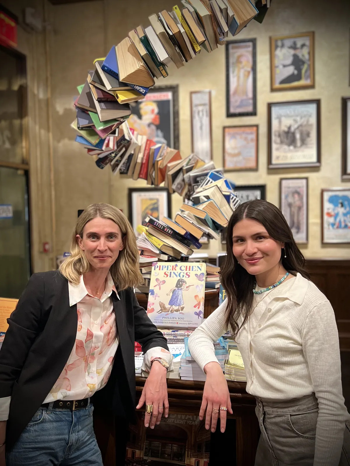 Maris Pasquale Doran and Phillipa Soo beside a display of Piper Chen Sings at The Drama Bookshop.