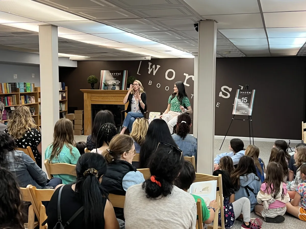 Maris Pasquale Doran reading Piper Chen Sings aloud to children seated on the floor.