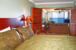 A spacious master bedroom with a king bed, crisp white linens, and sliding doors opening to a lush garden. Soft natural light fills the room, creating a peaceful, restful atmosphere.