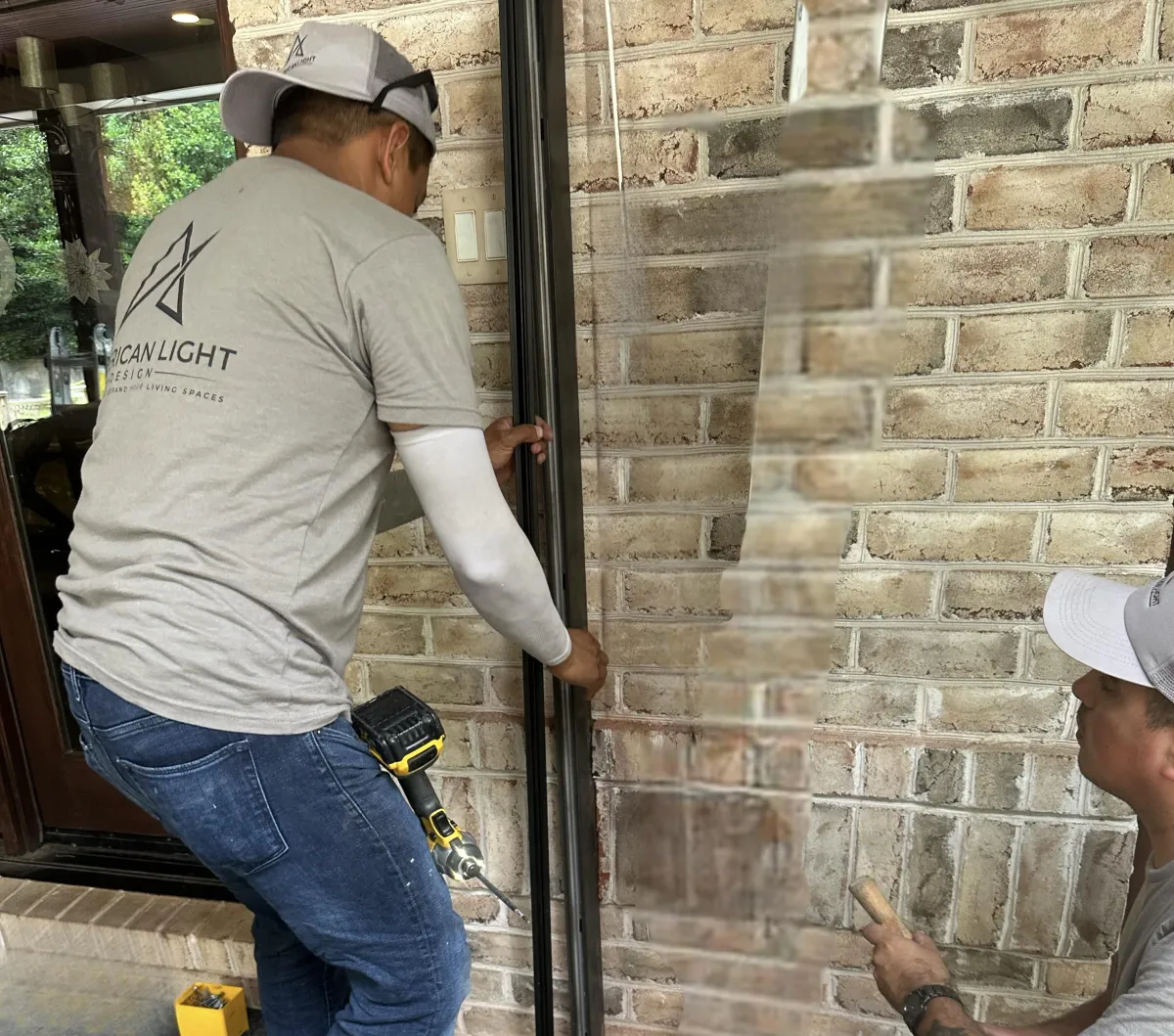 A photo of two American Light Design team members working to install a MagnaTrack Motorized System. 