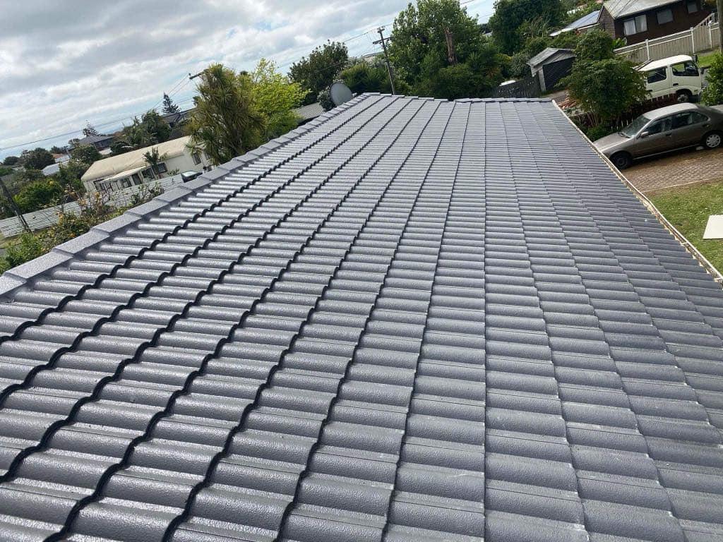 Freshly installed concrete tile roof with clean, uniform tiles under cloudy sky