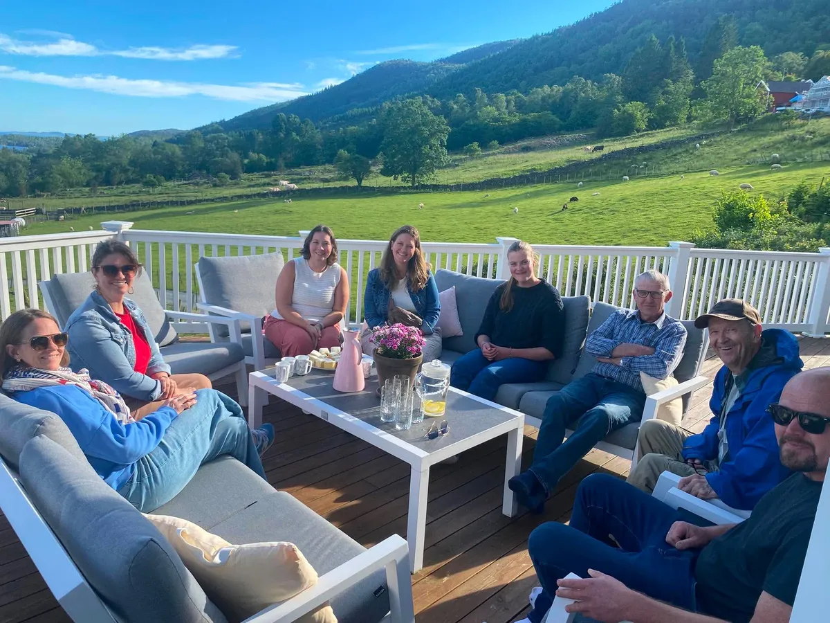 Family gathering on a sunny patio overlooking the Norwegian countryside