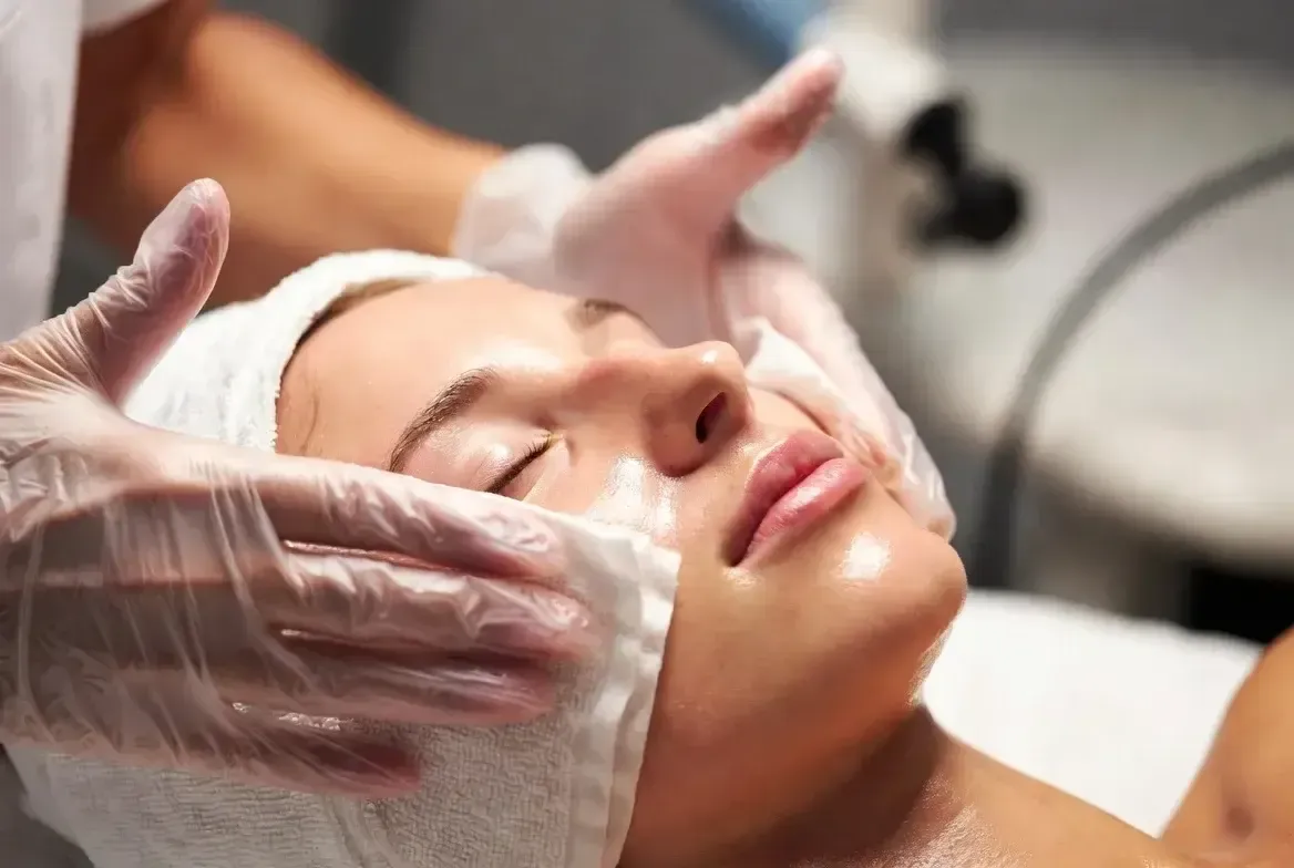 Gloved aesthetician gently wipes or applies product to a patient’s face during a Glow N Go Facial treatment.
