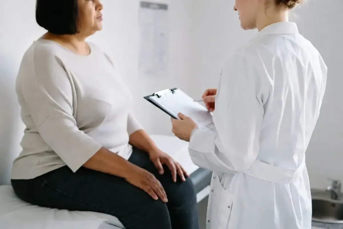 Female healthcare provider in a white coat reviews a medical weight loss plan with a patient during a consultation in a clinical setting.