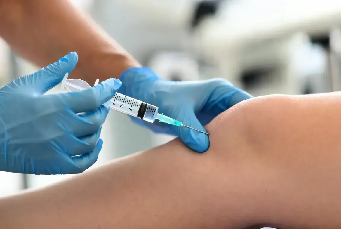 Gloved medical professional administers a PRP injection into a patient’s knee for joint pain relief in a clinical setting.