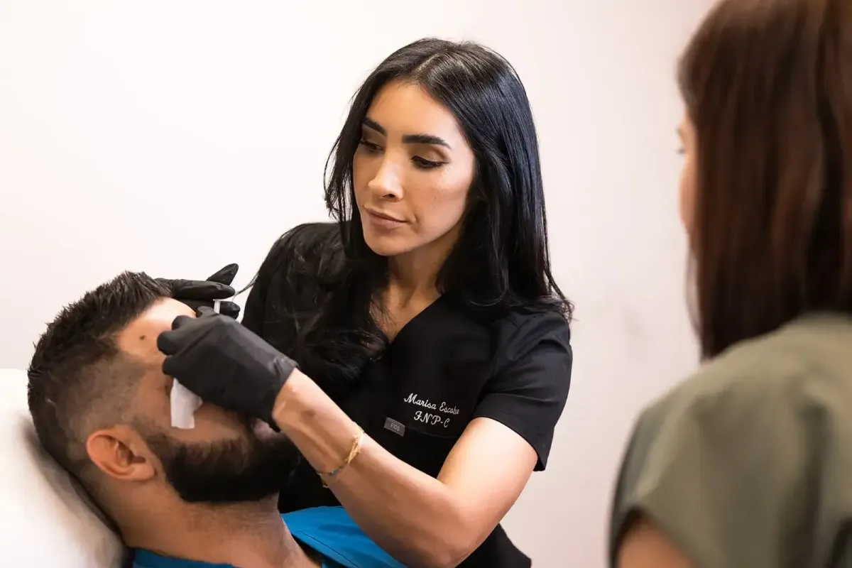 Aesthetic instructor demonstrating biostimulator injection technique on a male patient during a hands-on training session at Chrome Aesthetics Academy.