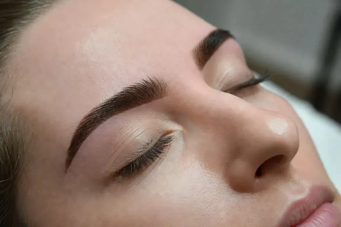 Close-up of a woman’s face with freshly tinted brows and lashes, eyes closed, showcasing results of a brow and lash tint treatment at Chrome Aesthetics.
