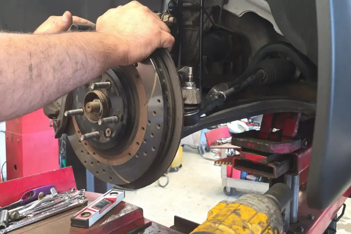 Mechanic inspecting a car brake rotor and caliper at Deals Tires Brake shop