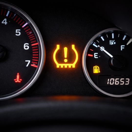 Tire pressure warning light illuminated on a car dashboard indicating a TPMS sensor issue