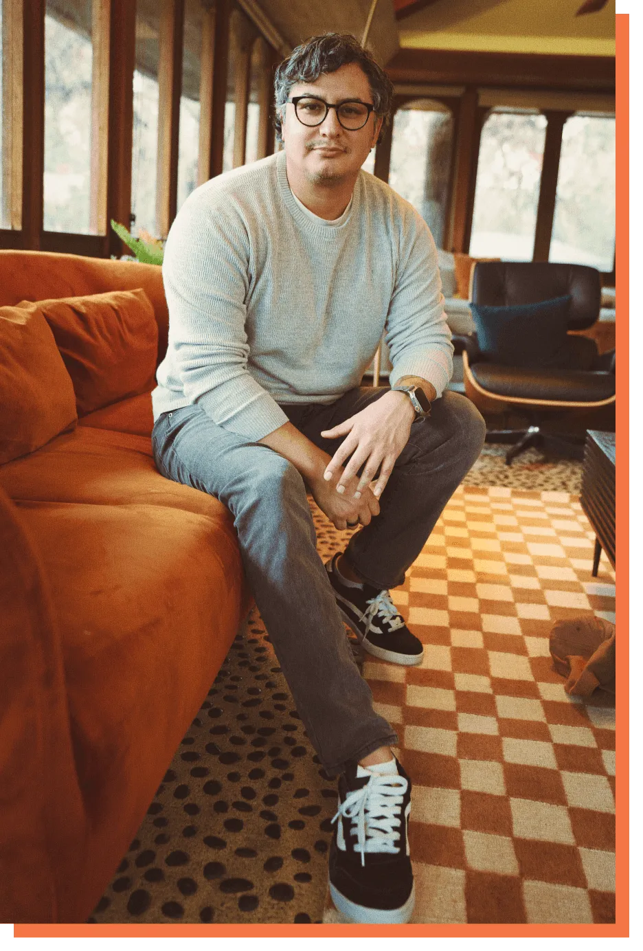 Portrait of Jesse Vasquez in his home smiling at camera wearing his signature vans shoes.