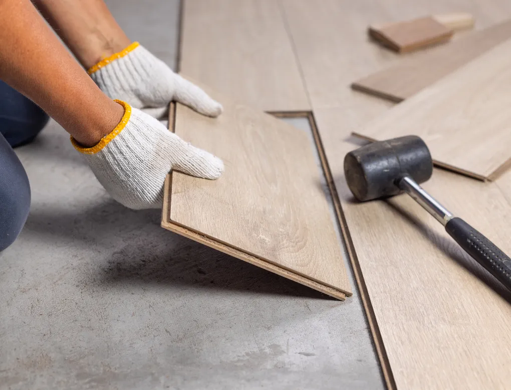 Professional handyman repairing kitchen cabinet in modern white kitchen providing expert home repair and maintenance services for homeowners in North Carolina