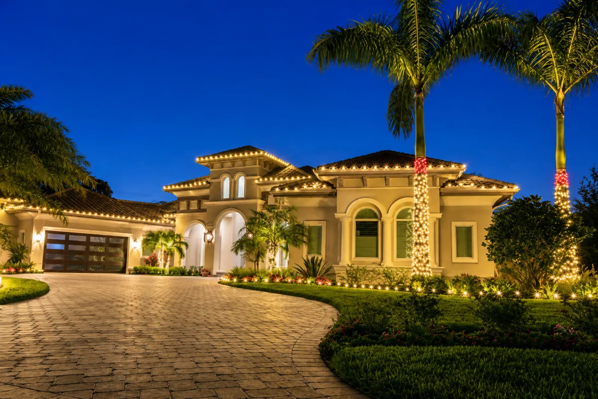 Custom Christmas light design on a luxury home in Lakewood Ranch, Florida featuring warm white roofline lighting and palm tree wraps.