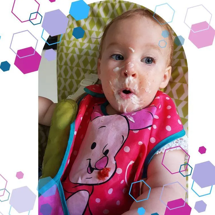 A Baby in a highchair with yoghurt around her mouth. She is happy and pulling a funny face. CubCare hexagons are shown around the outside of the image for brand purposes. Image is being used to advertise the Starting Solids Course.