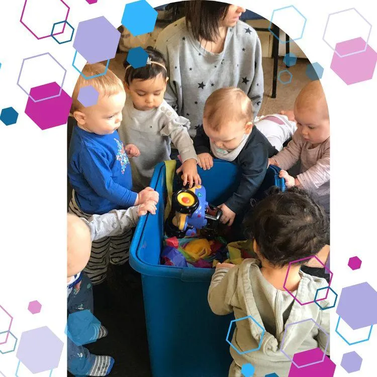 Three babies sitting on the floor surrounded with toys whilst Jilly reads them a story at a CubCare Wriggers Baby Yoga and Sensory class Welwyn Hatfield