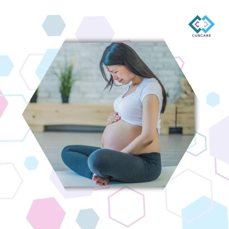 Hexgon image with a pregnant woman sitting on the floor holding and looking at her baby bump. At a CubCare Hypnobirhing class.