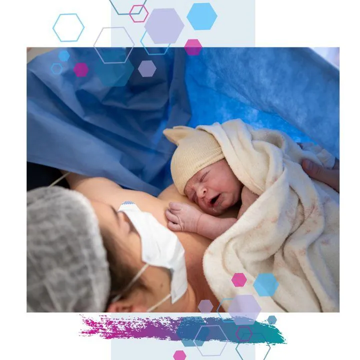 Mum and baby having skin to skin contact in theatre after a c-section birth. Baby has a blanket laid over them, and mum is wearing  cap and surgical mask.