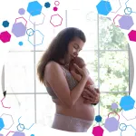 Pregnant person holding a newborn against their shoulder in soft light, symbolising calm, informed birth and recovery after completing the CubCare hypermobility course.