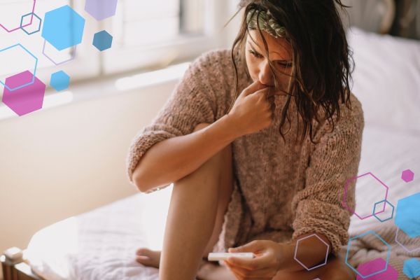Person holding a pregnancy test and looking worried in early pregnancy, reflecting concerns about spotting or brown discharge at 4–8 weeks.