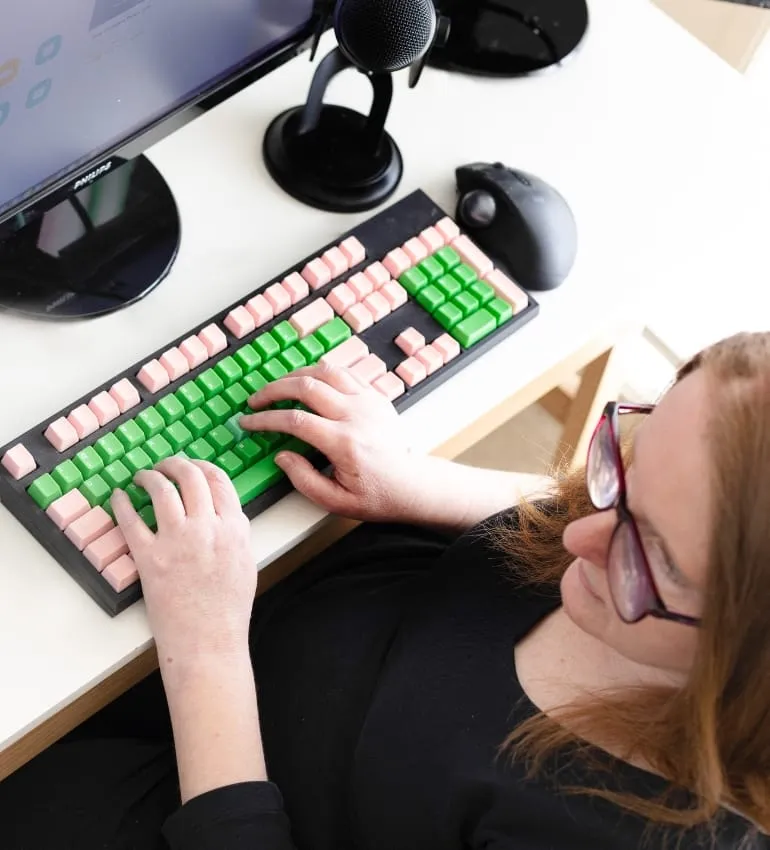 Overhead view of Ainslee Hooper typing on a colourful keyboard at her desk.