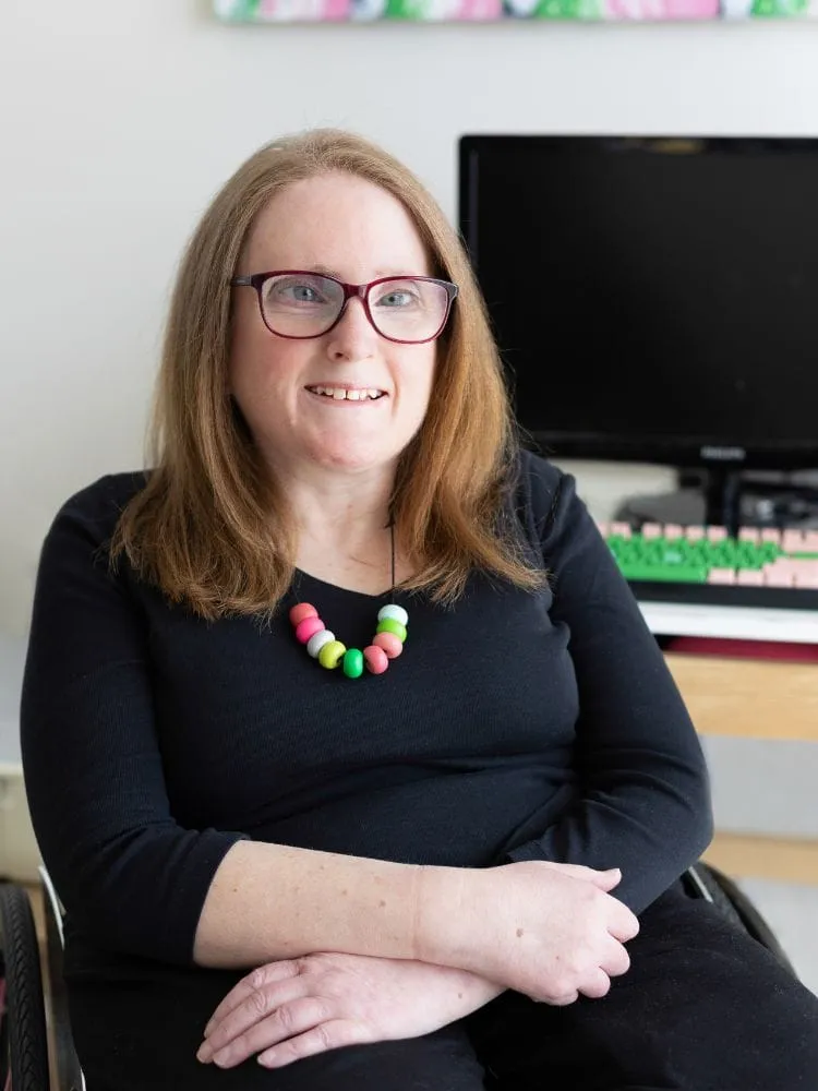 Ainslee Hooper smiling, wearing a black top and a colourful beaded necklace