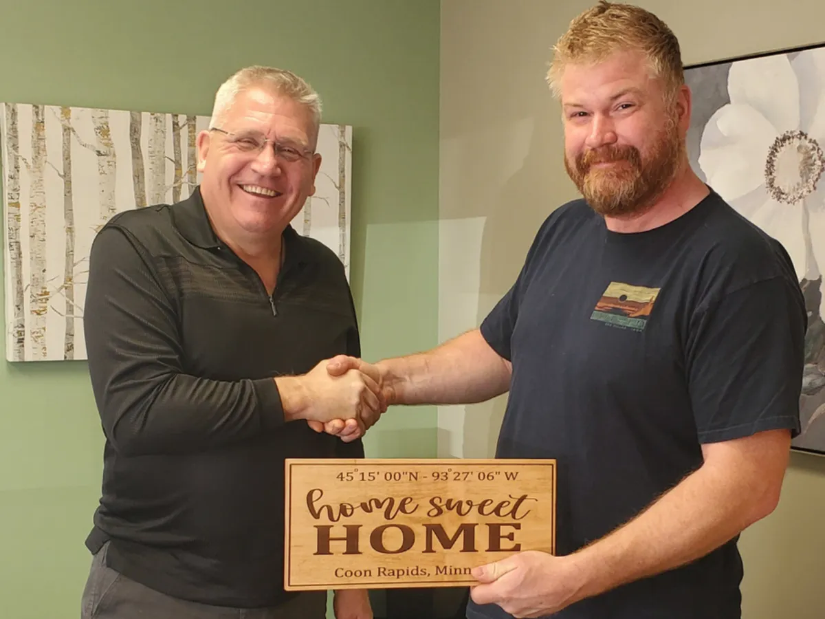 Veteran shaking hands with real estate agent in front of a home