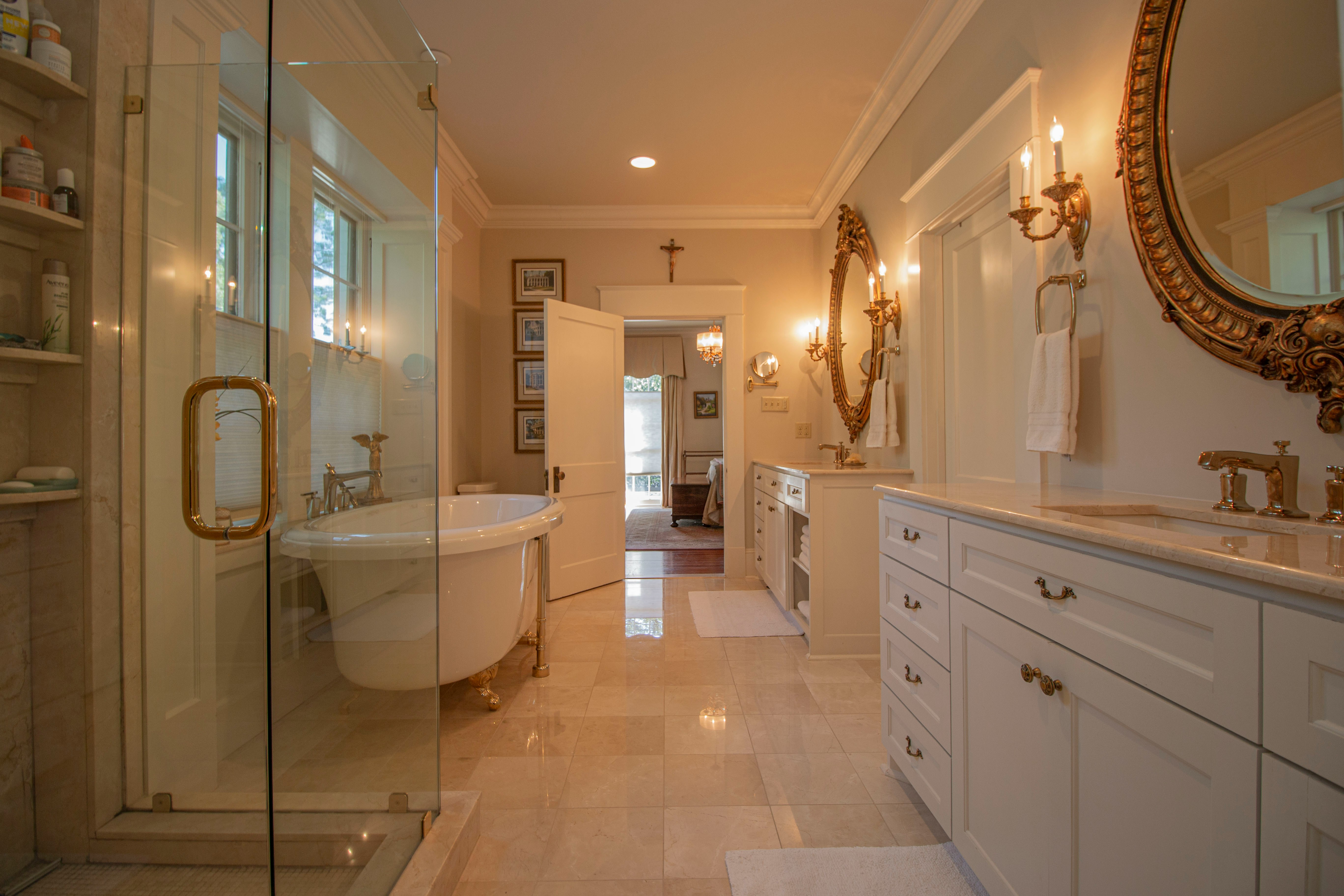 golden lighted bathroom with a shower, tub, sink, and golden framed mirror