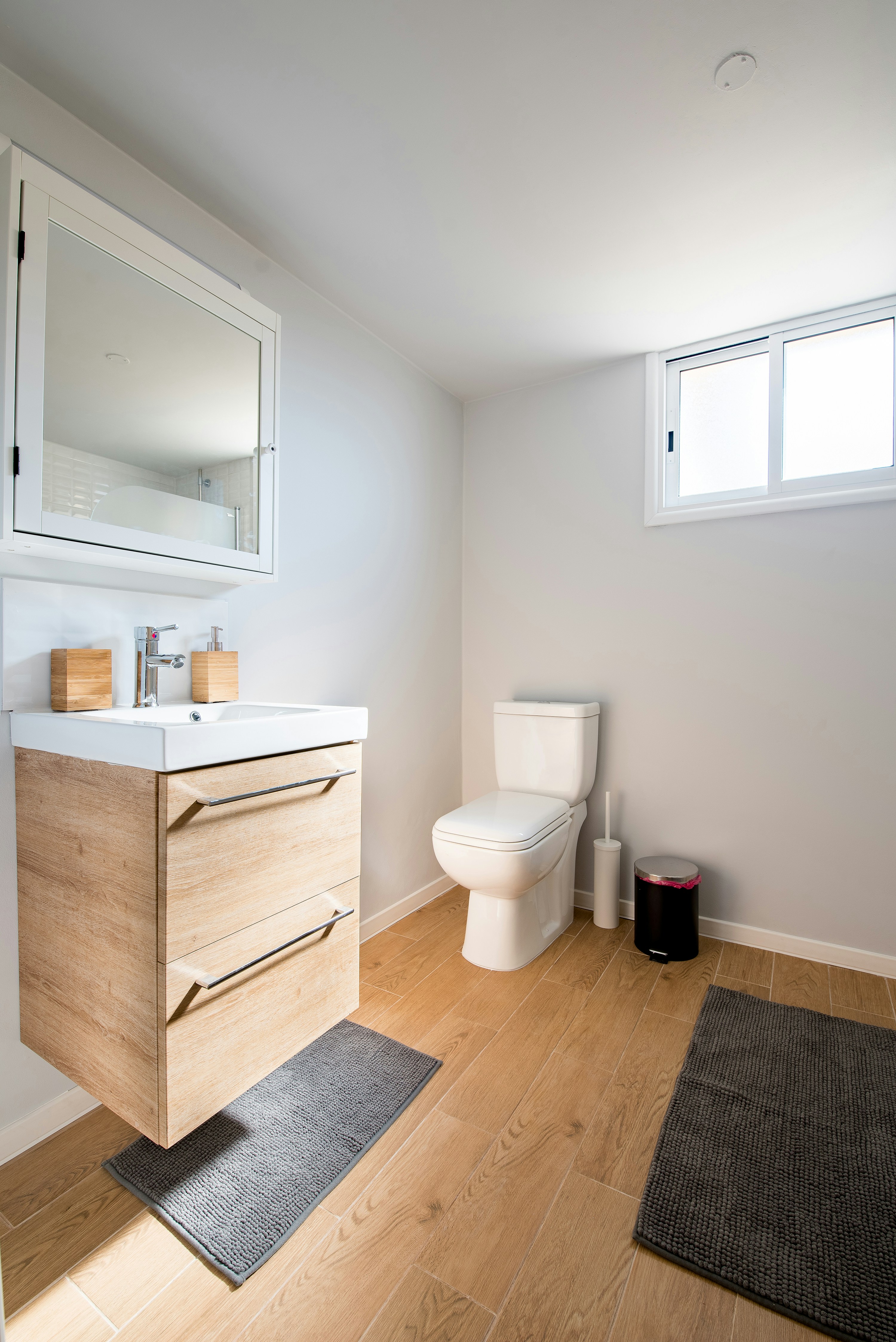 vinyl wood floor with a small sink with two storage spaces beneath it and a toilet bowl