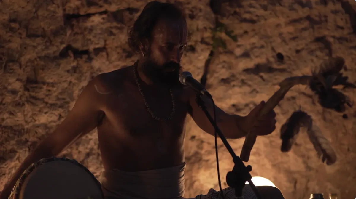 Tato Sáenz cantando con un tambor ante una pared de piedra