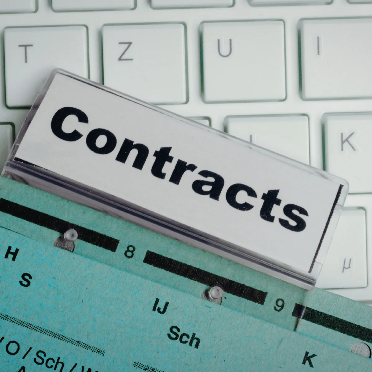 Contracts written on a folder tab with a laptop keyboard behind it.