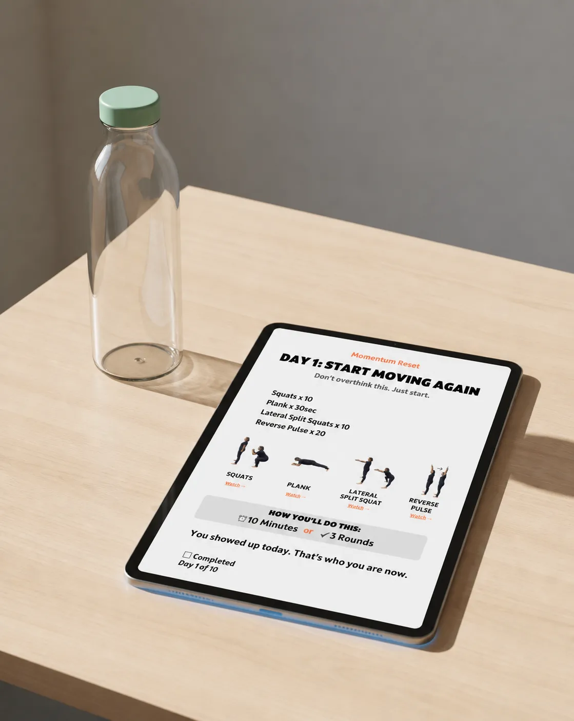 Tablet showing 10-day momentum reset PDF next to a water bottle